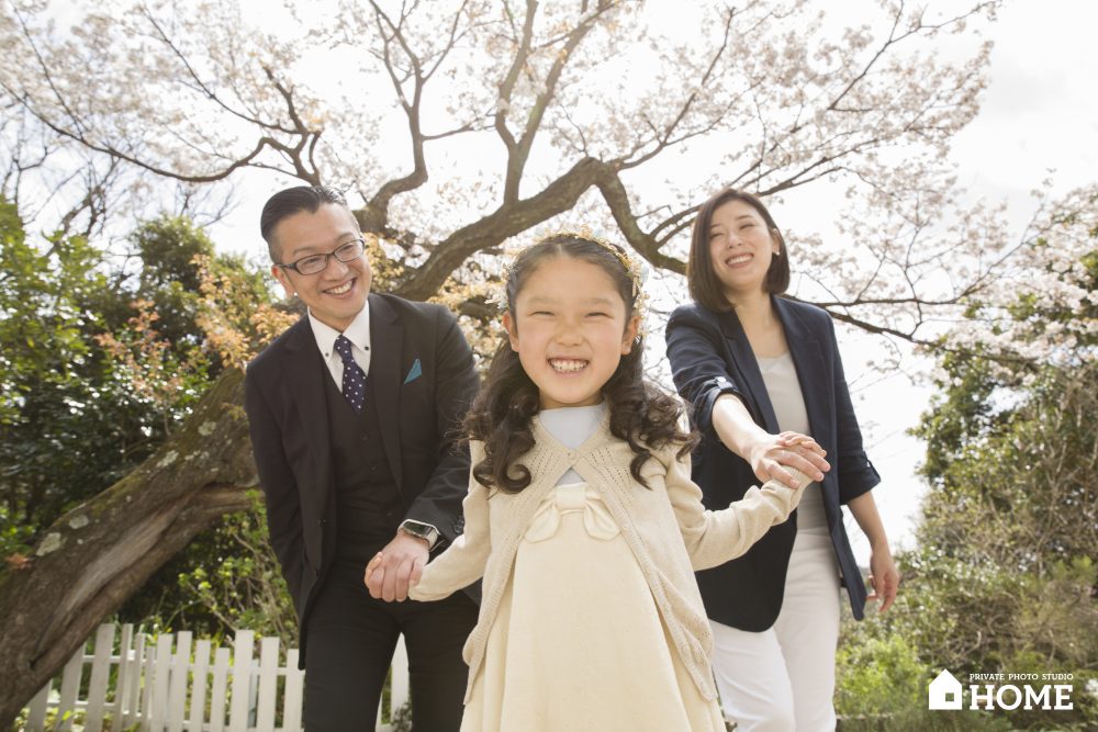 子供写真スタジオStudioHome鎌倉店の桜の木の下で家族が手をつないでいる写真。